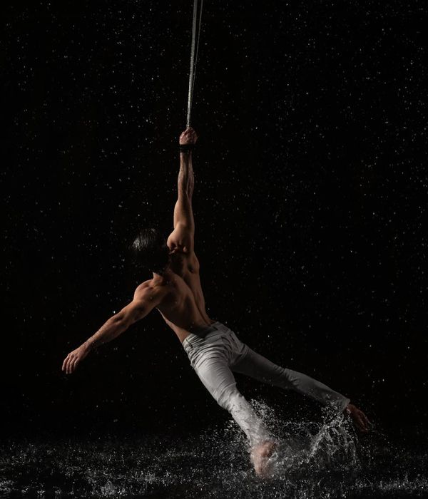 Man performing a controlled strength exercise in a dark studio setting